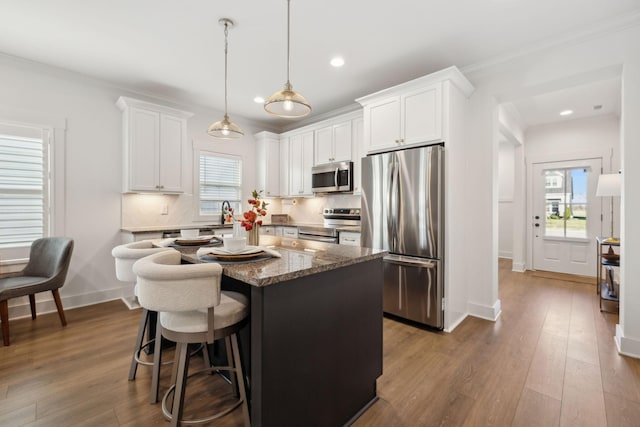 kitchen featuring dark wood finished floors, stainless steel appliances, tasteful backsplash, white cabinets, and a kitchen island