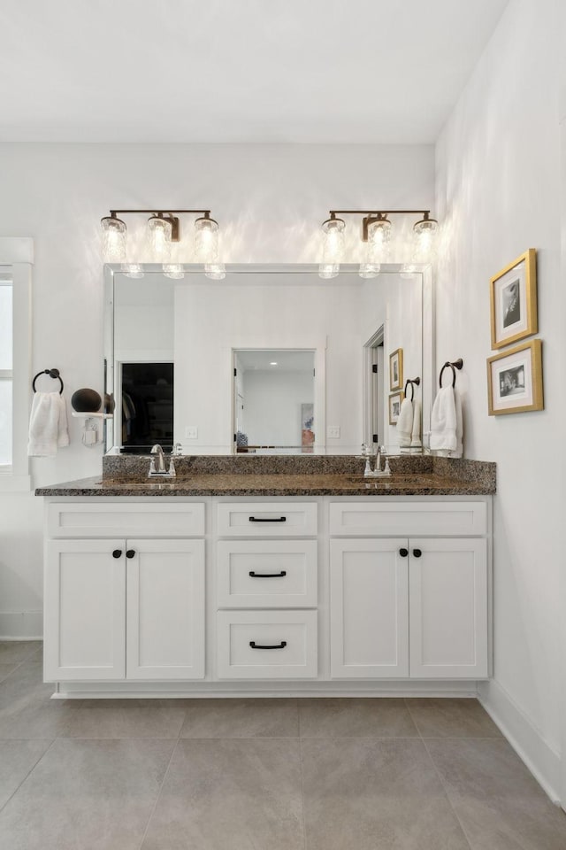 bathroom with double vanity, tile patterned flooring, baseboards, and a sink