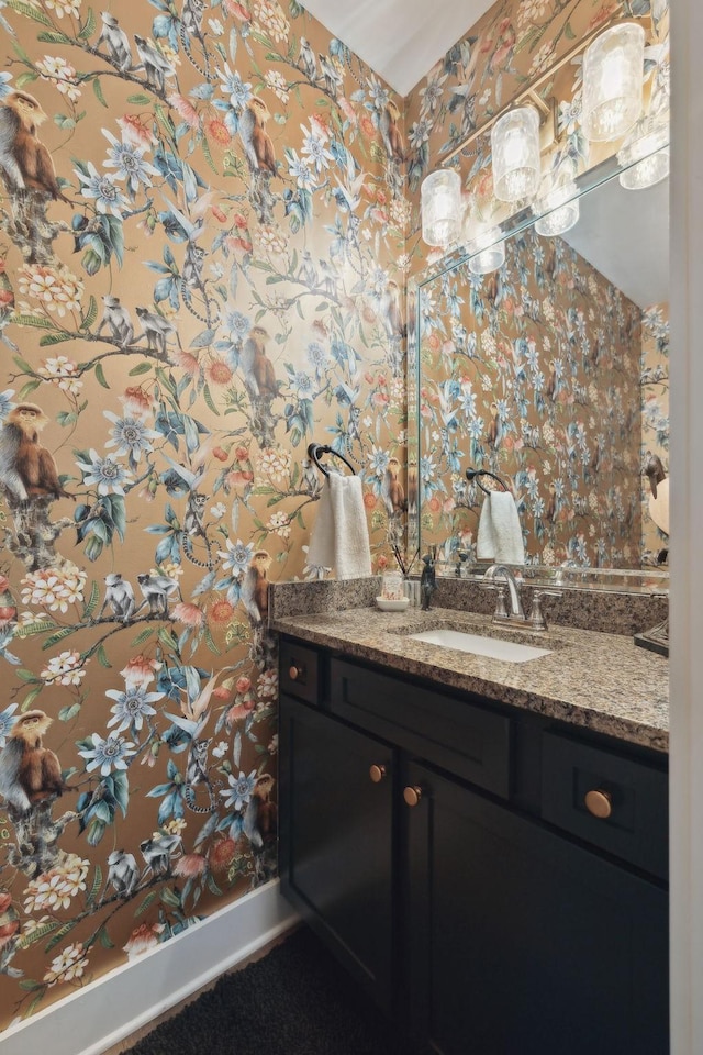 bathroom featuring wallpapered walls, baseboards, and vanity