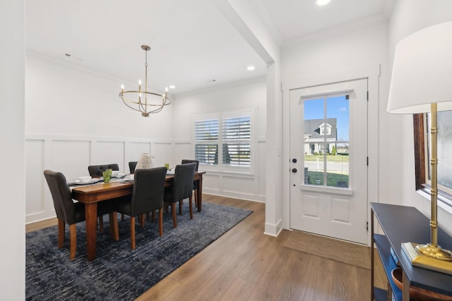 dining space featuring ornamental molding, wood finished floors, a chandelier, a decorative wall, and recessed lighting