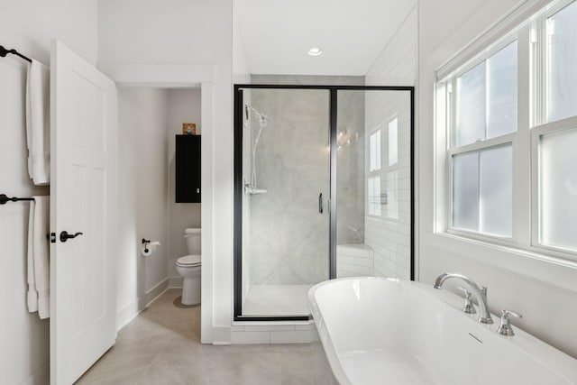 bathroom featuring a soaking tub, toilet, a shower stall, baseboards, and tile patterned floors