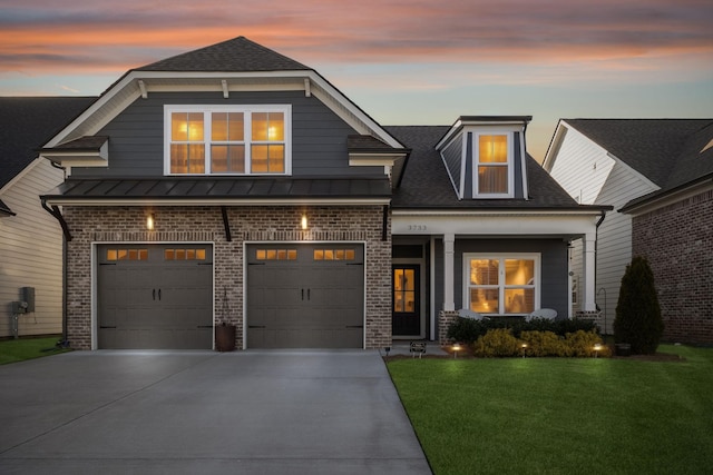 view of front of house featuring a front yard, concrete driveway, brick siding, and a standing seam roof