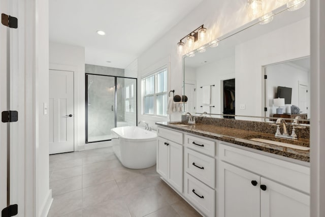 bathroom featuring a freestanding tub, tile patterned flooring, a sink, and a shower stall