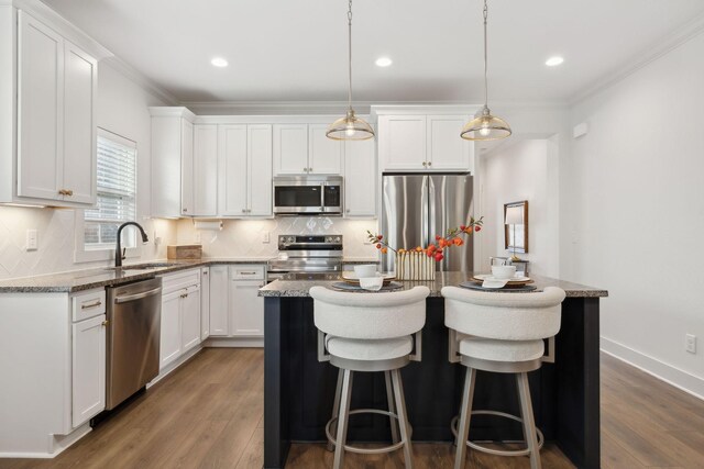 kitchen with decorative backsplash, stainless steel appliances, a sink, and a center island