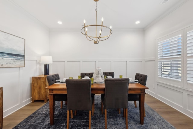 dining room with crown molding, a decorative wall, and wood finished floors