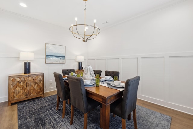 dining space featuring recessed lighting, a decorative wall, an inviting chandelier, ornamental molding, and wood finished floors