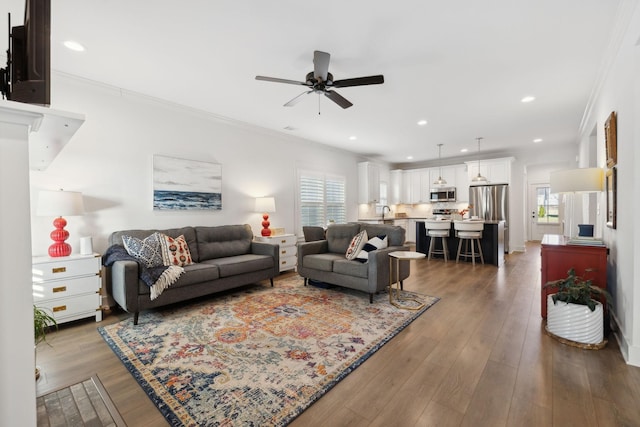 living area with a ceiling fan, recessed lighting, crown molding, and wood finished floors