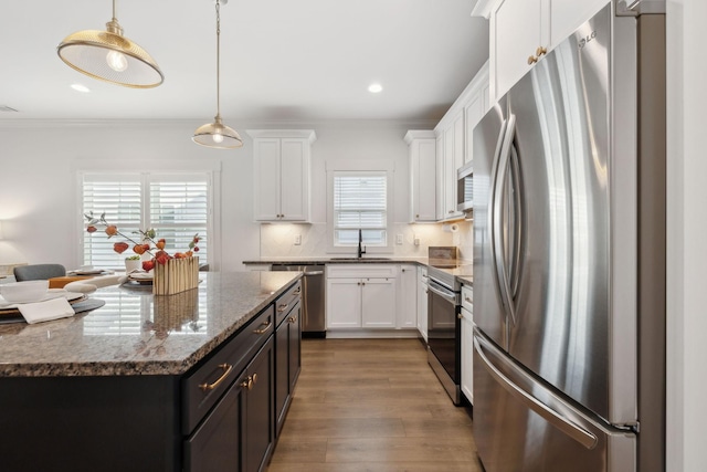 kitchen with appliances with stainless steel finishes, white cabinets, a sink, and ornamental molding