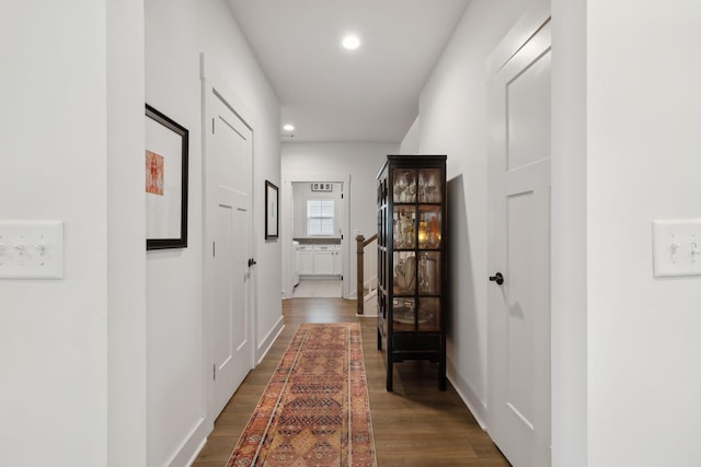 hall featuring baseboards, dark wood-type flooring, and recessed lighting