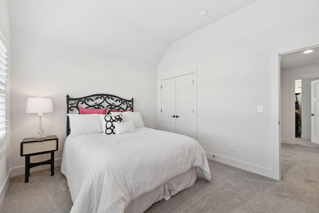 carpeted bedroom with vaulted ceiling, a closet, and baseboards