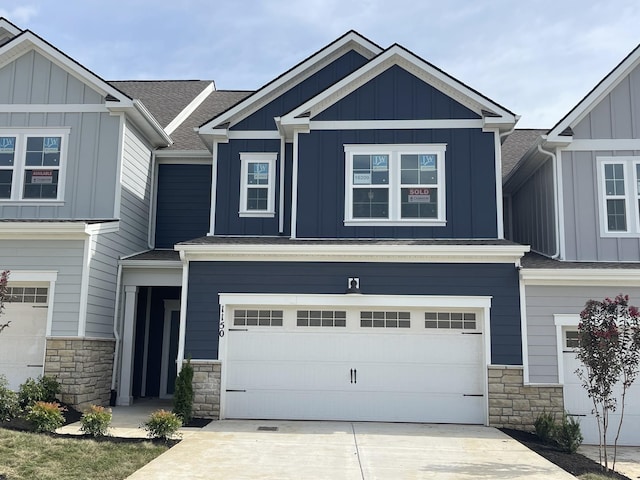 craftsman inspired home with a garage, concrete driveway, stone siding, roof with shingles, and board and batten siding