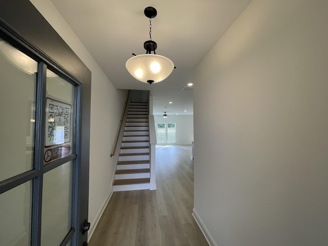 hall with stairway, wood finished floors, and baseboards