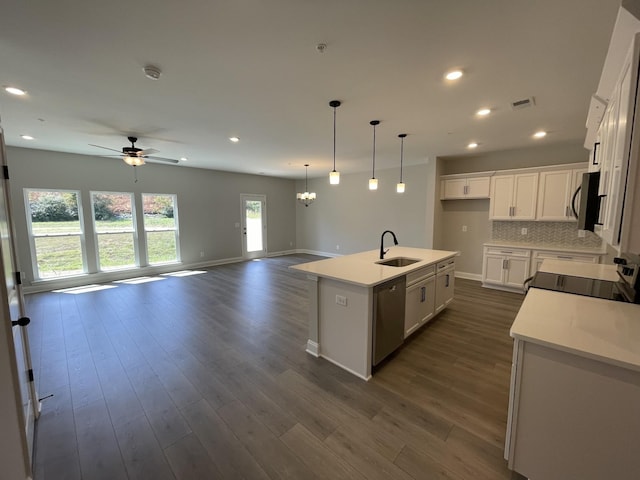 kitchen with dark wood finished floors, decorative backsplash, appliances with stainless steel finishes, open floor plan, and a sink