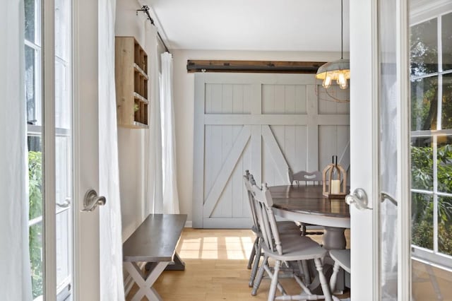 dining room featuring a barn door, wood finished floors, and a notable chandelier