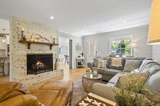 living area with light wood-type flooring, a brick fireplace, and recessed lighting