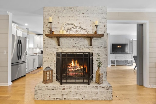 interior details featuring crown molding, a fireplace, backsplash, appliances with stainless steel finishes, and wood finished floors