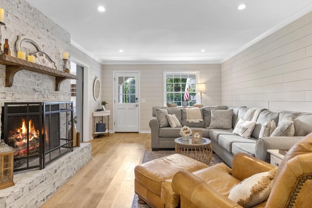 living area featuring ornamental molding, a fireplace, recessed lighting, and light wood-style floors