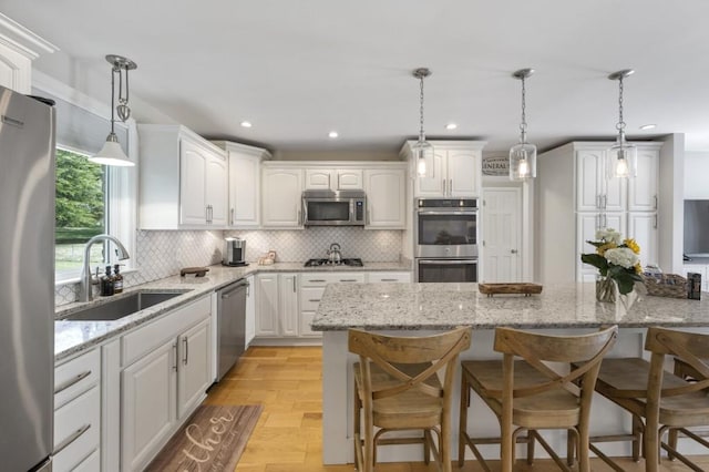 kitchen featuring stainless steel appliances, a breakfast bar, a sink, white cabinetry, and tasteful backsplash