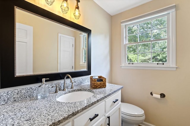 half bath with toilet, vanity, and baseboards