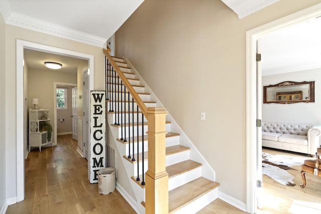 staircase featuring ornamental molding, baseboards, and wood finished floors