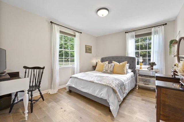 bedroom with multiple windows, light wood-style flooring, and baseboards