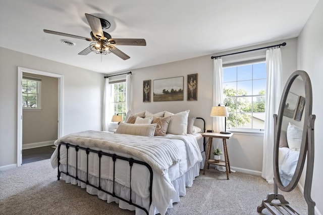 carpeted bedroom featuring ceiling fan, multiple windows, baseboards, and visible vents