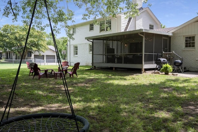 rear view of property featuring brick siding, fence, a sunroom, a yard, and a chimney