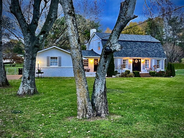 dutch colonial with roof with shingles, brick siding, a chimney, a gambrel roof, and a front yard