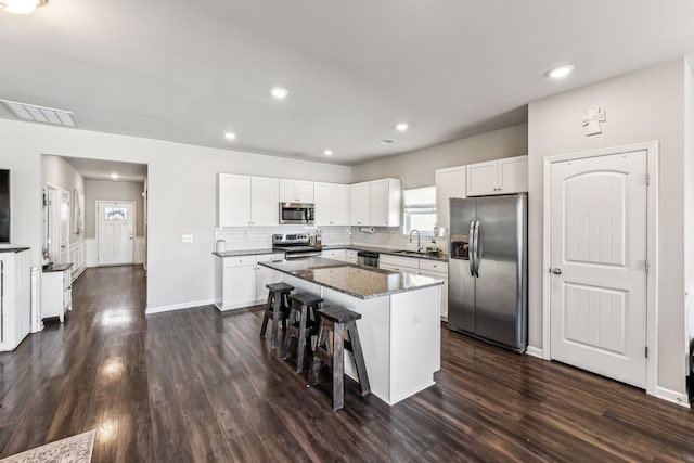 kitchen featuring tasteful backsplash, visible vents, a center island, stainless steel appliances, and a sink