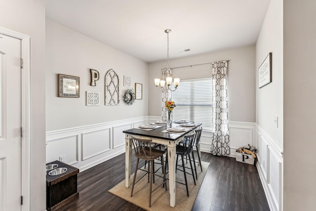 dining area featuring a chandelier, a wainscoted wall, dark wood finished floors, and visible vents