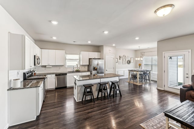 kitchen with white cabinets, decorative backsplash, appliances with stainless steel finishes, dark wood-style flooring, and a sink