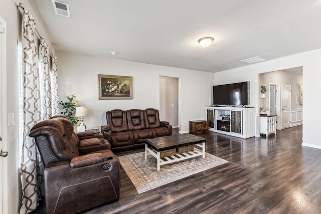 living area with baseboards, a lit fireplace, visible vents, and wood finished floors