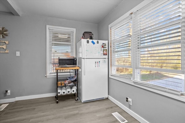 interior space with baseboards, visible vents, and wood finished floors