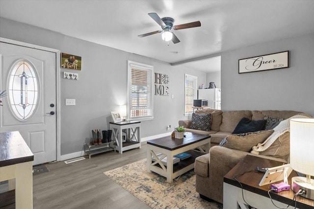 living room featuring baseboards, a ceiling fan, and wood finished floors