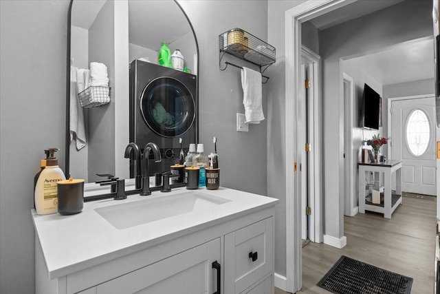 bathroom featuring baseboards, vanity, stacked washing maching and dryer, and wood finished floors