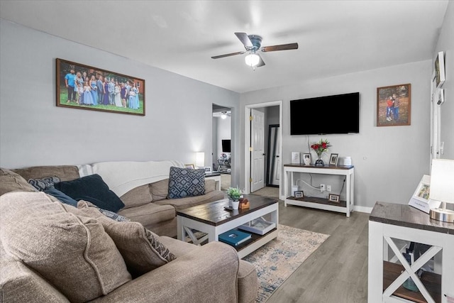 living area featuring a ceiling fan, baseboards, and wood finished floors