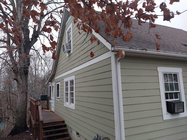 view of home's exterior featuring a shingled roof, cooling unit, and a wooden deck