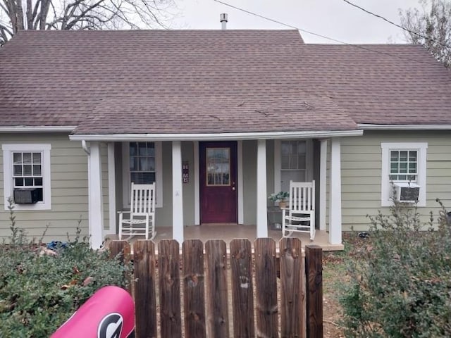 view of front facade featuring fence, a porch, and roof with shingles