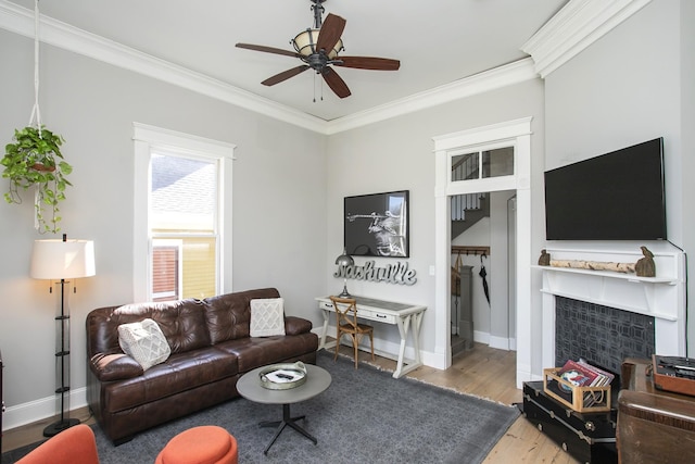 living area with ceiling fan, baseboards, crown molding, and wood finished floors