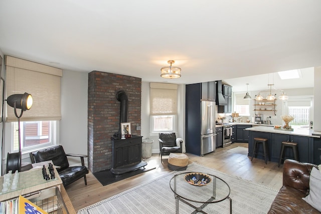 living room with light wood-type flooring, a wood stove, and a skylight