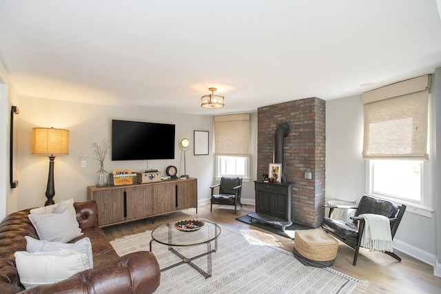 living area featuring wood finished floors, a wood stove, and baseboards