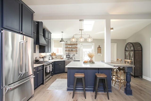 kitchen with premium appliances, a breakfast bar area, light countertops, a sink, and wall chimney exhaust hood