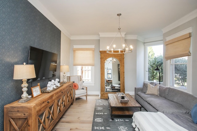 living area with baseboards, arched walkways, ornamental molding, an inviting chandelier, and light wood-style floors