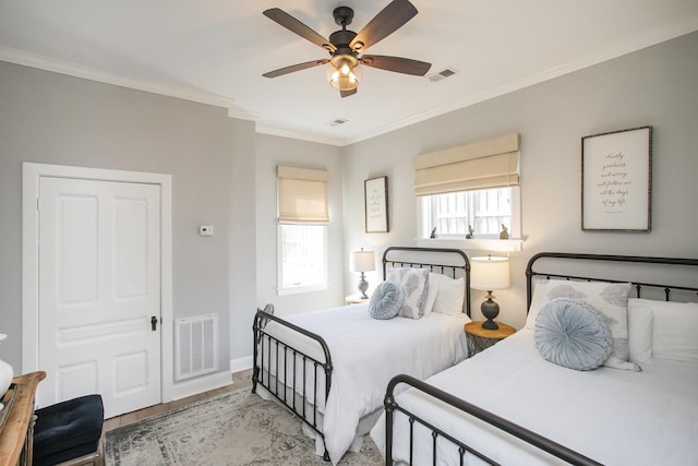 bedroom featuring ceiling fan, visible vents, baseboards, light wood-style floors, and crown molding