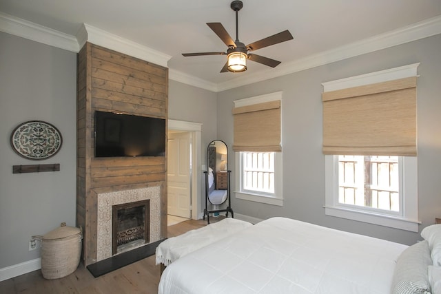 bedroom featuring baseboards, a fireplace, ornamental molding, and wood finished floors