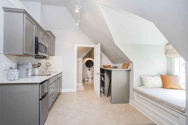 kitchen featuring decorative backsplash, stainless steel microwave, gray cabinets, and a sink