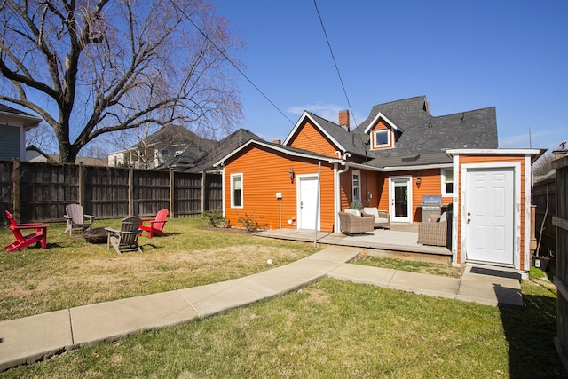 back of property featuring a fire pit, a lawn, and fence