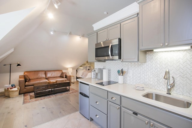 kitchen with gray cabinets, stainless steel microwave, a sink, and open floor plan