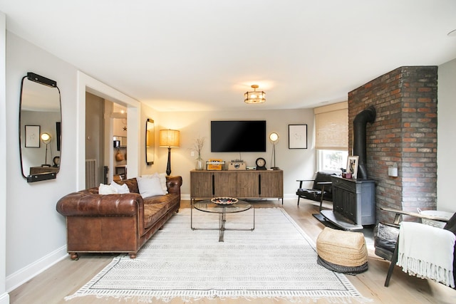 living area featuring baseboards, a wood stove, and light wood-style floors