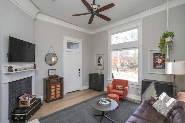 living room with a fireplace, baseboards, crown molding, and wood finished floors